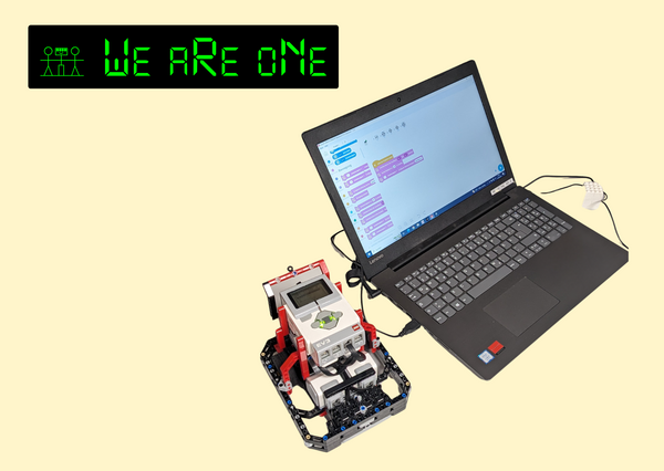 Bild vergr&ouml;&szlig;ern: Das Bild zeigt einen Laptop, neben dem auf der linken Seite ein Lego Roboter steht. Oben links in der Ecke ist das Logo des Vereins We are one zu sehen.